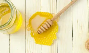 Słoik z miodem i plastrem miodu na drewnianym tle. Czy pies może jeść miód? To pytanie nurtuje wielu właścicieli czworonogów.
